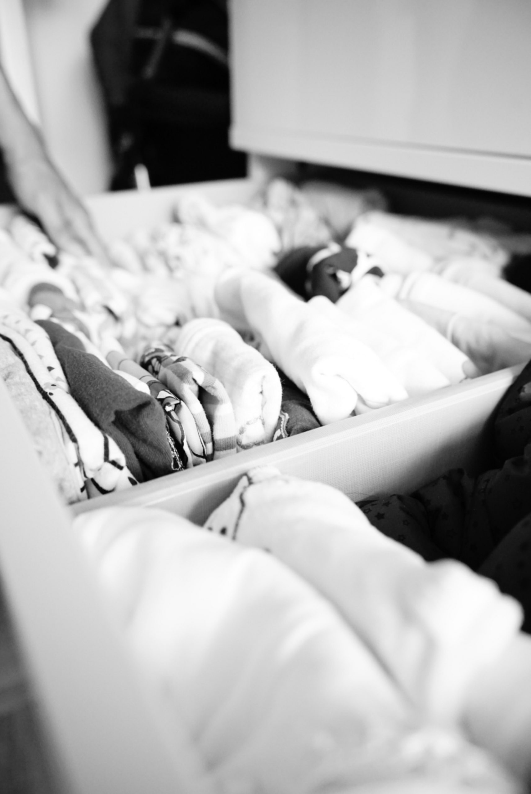 Schublade mit Kinderkleidung in der gerade jemand einräumt, schwarzweiß Foto